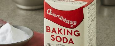 Imagen of A box of baking soda with a red and white label sitting on a counter next to a measuring cup