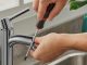Imagen of A person tightening a screw on a kitchen faucet with a screwdriver